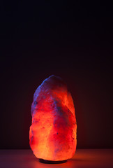Illuminated himalayan salt lamp on wooden table