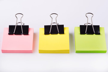 self-stick notes and binder clips on a white background
