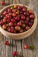 Red gooseberry in a bowl on wooden surface