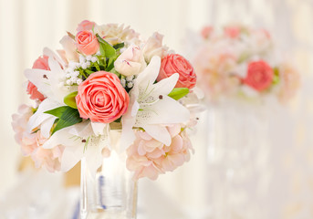 Served table for event dinner, decorated with floral compositions in vases in pink and coral shades. Wedding bouquet