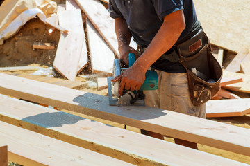 Close-up of a carpenter using a circular saw to cut a large board of wood