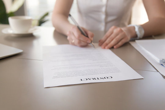 Close up view of businesswoman signing business legal document, female hands putting signature on official paper, concluding deal for services, work or supplies, focus on financial contract on table