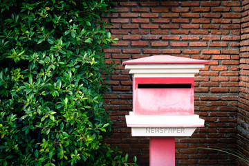 Outbox outside the house with bushes and orange brick walls.