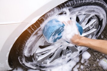Hand image is holding sponge and car wash.Wheel area. Car wash concept.