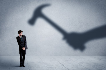 Business person afraid of a shadow hand holding hammer concept