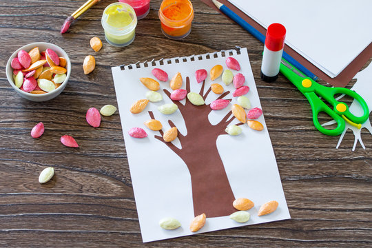 Postcard autumn tree with multi-colored leaves of a pumpkin leaf on a wooden background. Children's art project, craft for children. Craft for kids.