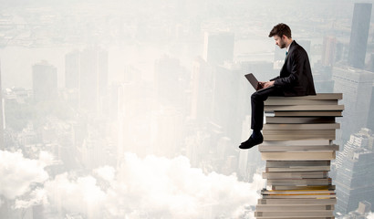 Student in city sitting on stack of books