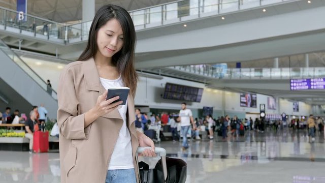 Woman use of cellphone and holding passport in airport