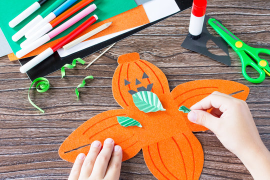 Create a gift box of Halloween pumpkin. The child cuts out the details of the application of the box. Children's art project, craft for children. Craft for kids.
