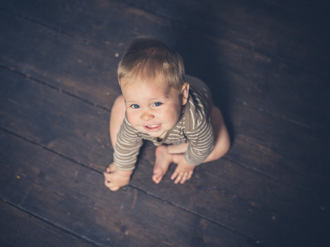 Little baby sitting on floorboards