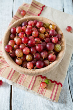 Red gooseberry in a bowl on wooden surface