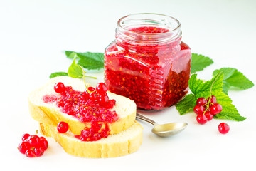 Homemade jam and white bread. Glass jar with red currant jam on a white background. Preserved berry.