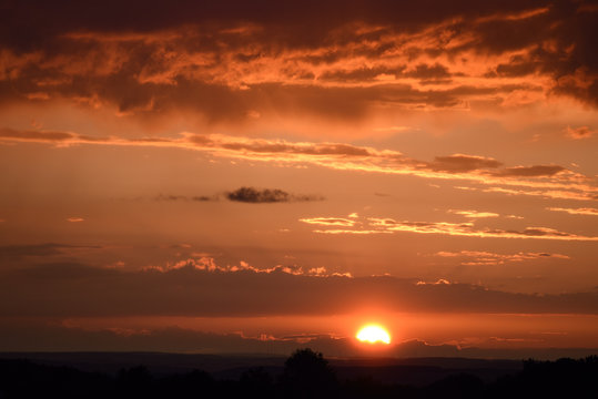 Sonnenuntergang mit kr&auml;ftigenund intensiven Abendrot mit Windr&auml;dern im Hintergrund