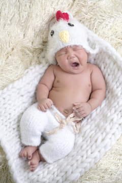Portrait of Asia boy newborn is lay down yawn on white fur background with bear  .