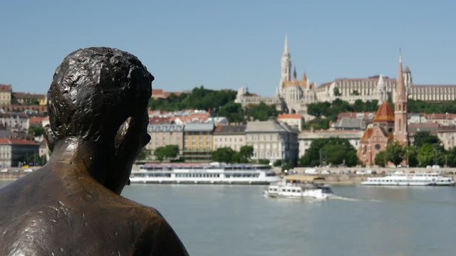 Statue of Attila Jozsef, one of the country's best-loved 20th century poets in Budapest with a boat passing by in Hungary