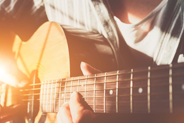 close up shot of strings and guitarist hands playing guitar over black - selective focus with...