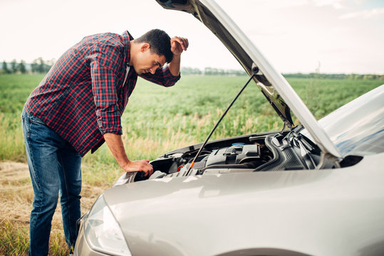 Tired man tries to repair a broken car