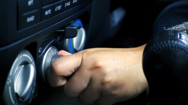Close-up of female hand adjusting button control air conditioning on a vehicle's dashboard. Slowmotion shot
