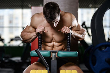 Muscular handsome athletic bodybuilder fitness model posing after exercises in gym on diet .