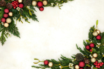 Christmas background border with gold and red bauble decorations, holly, mistletoe, ivy, juniper fir and pine cones on old parchment paper.