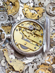 open silver pocket watch on pile of spare parts