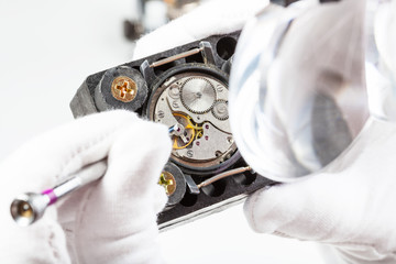 watchmaker in head-mounted magnifier adjusts watch