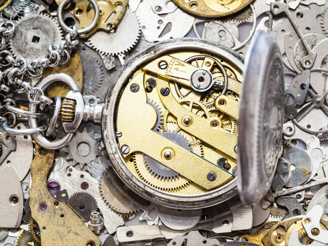 open silver pocket watch on heap of spare parts