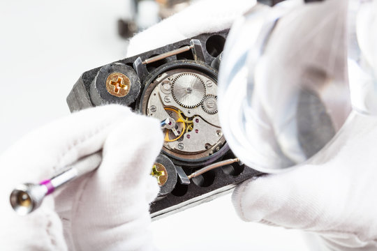 watchmaker in head-mounted magnifier adjusts watch
