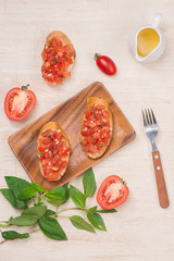 Tasty Italian bruschetta with  bread topped with tomato and herbs on wooden board