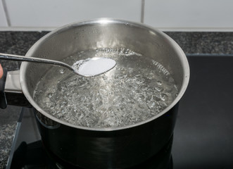 Salz in das kochende Wasser werfen