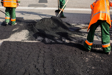 Workers on Asphalting paver machine during Road street repairing works. Street resurfacing. Fresh asphalt construction. Bad road