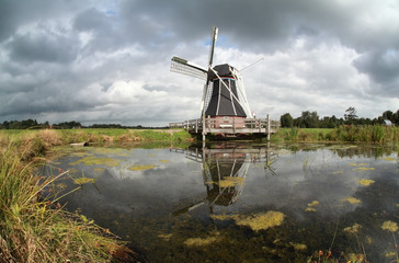 Fototapeta premium windmill reflected in lake water