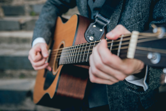 Man's hands playing acoustic guitar. Background