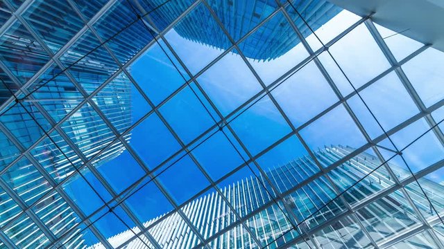 Time lapse of Looking up through the sun roof at office building at clouds and sunshine.