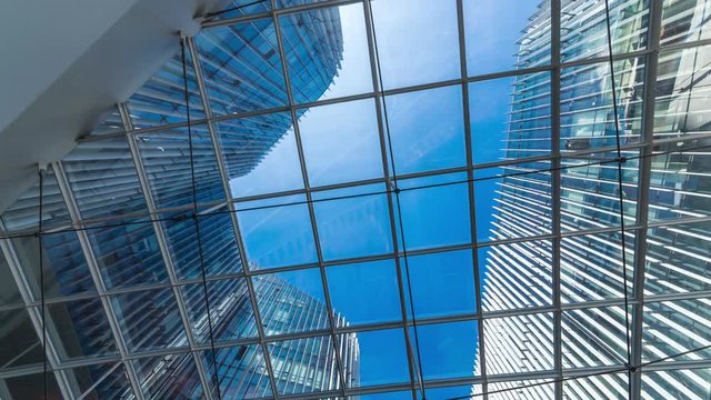 Time lapse of Looking up through the sun roof at office building at clouds and sunshine.