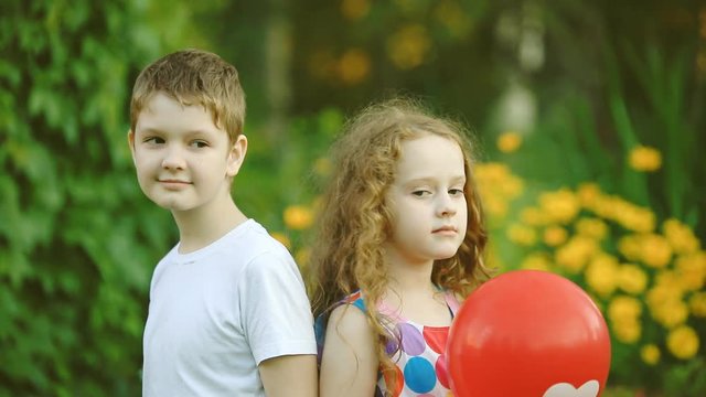 Little boy gift his girlfriend balloons with heart in summer park. Valentines day background.