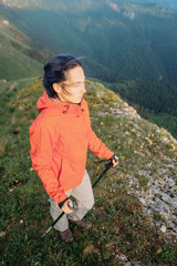 Naklejka na ściany i meble Hiker woman with trekking poles in mountains.