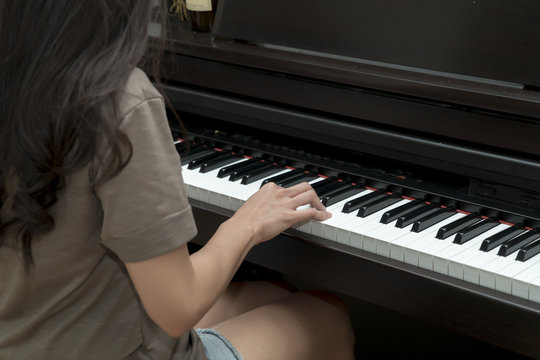 Side view of Young woman playing piano