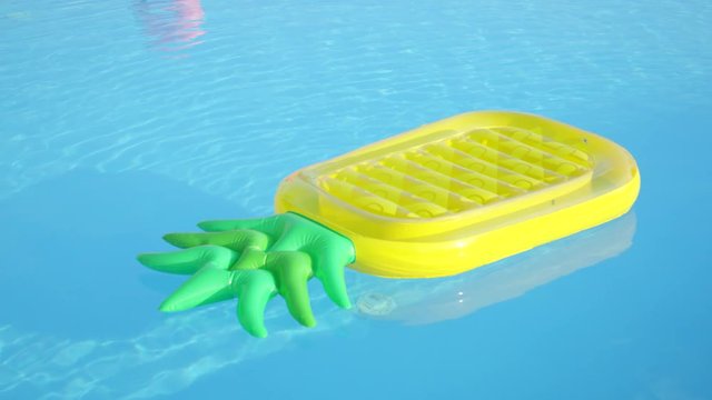 CLOSE UP: Empty Inflatable Pineapple Floatie Floating In Pool Water On Gorgeous Summer Morning. Colorful Fun Pineapple Pillow Floating On Water Surface In Empty Pool