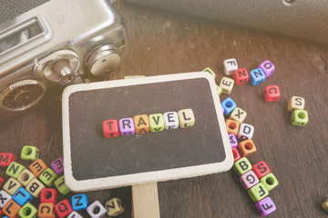 travel word block, compass and vintage camera on wooden background ideal for holiday and vacation concept