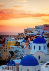 townscape of Oia, traditional greek village of Santorini, with blue domes of churches at sunset,...