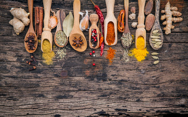 Various of spices and herbs in wooden spoons. Flat lay of spices ingredients chilli ,pepper corn, garlic, thyme, oregano, cinnamon, star anise, nutmeg, mace, ginger and bay leaves on shabby wooden..