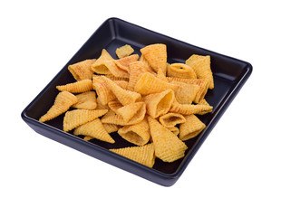 Crunchy corn snacks on black dish on a white background.