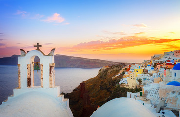 cityscape of Oia, traditional greek village of Santorini, with white bellfry at sunset, Greece, retro toned - obrazy, fototapety, plakaty