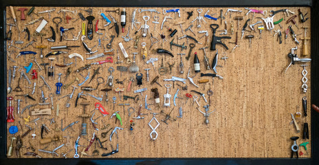 A collection of many different bottle openers displayed on a cork board