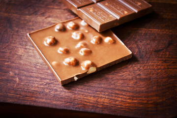 Broken chocolate bar with hazelnuts on wooden table