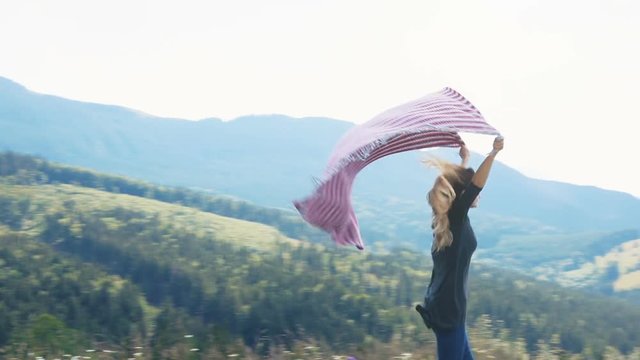 Young woman running high top mountains forest hands holding blanket above head wind blowing flying windy summer happiness carefree side full view peak cheerful joying joy having fun smiling traveling