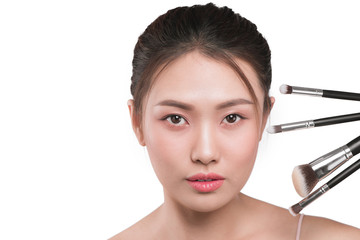 Fototapeta premium A portrait of young pretty isolated on white background women holding makeup brushes