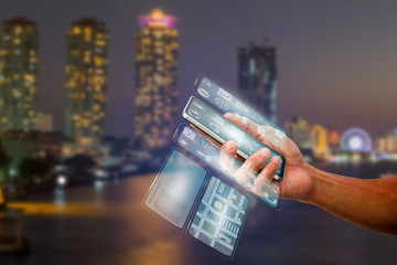 Man's hand holding smartphone with transparent multi screen on blurred city night light,...
