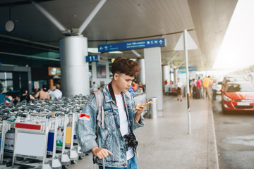 Portrait of smiling man texting while waiting for taxi in the airport